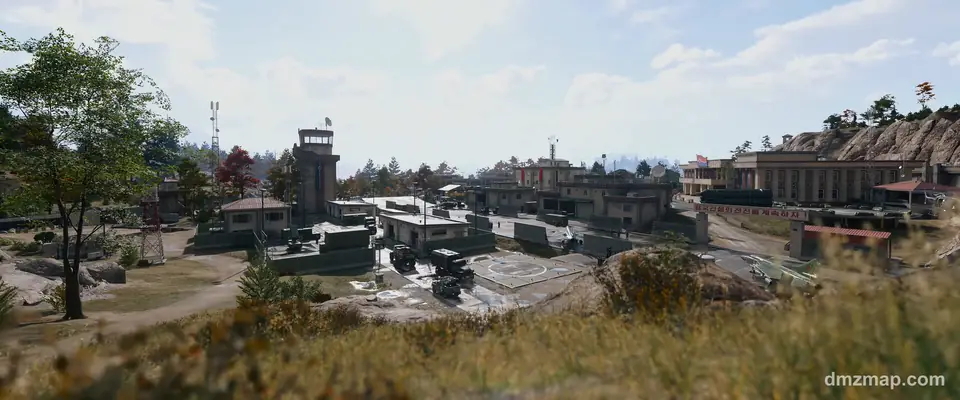Chang-san Air Base seen over tall grass in MW4 DMZ: the control tower, a helipad with military trucks, a parked jet and the columned headquarters below a rocky hill